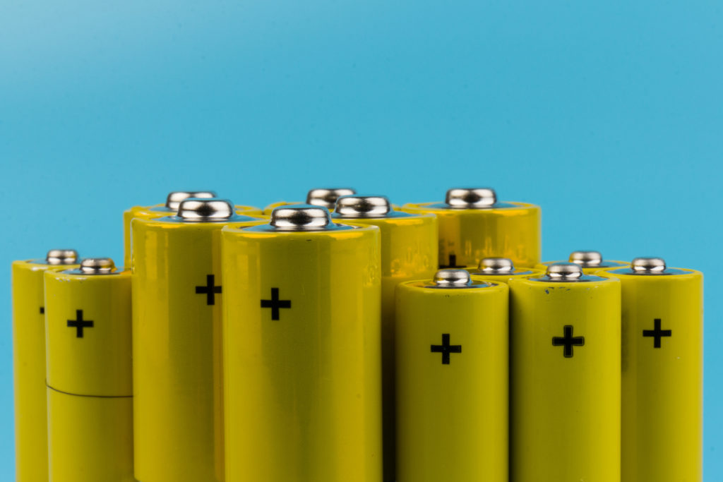 Photo of gray-yellow alkaline AA batteries on blue background. Recycling of rechargeable NiMH batteries. The most popular size of accumulators. Copy space.
